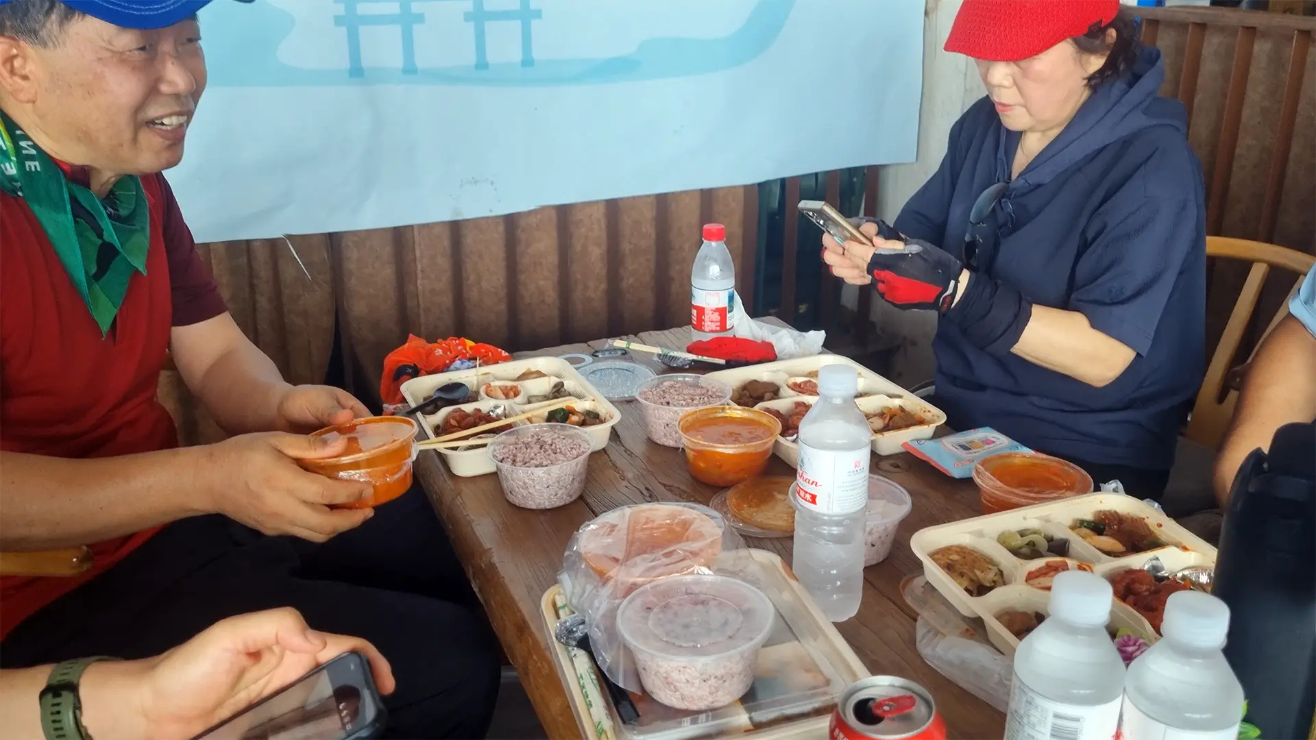칭다오 노산의 웅장한 바위산과 바다가 보이는 배경에서 정갈한 한식 도시락과 칭다오 맥주